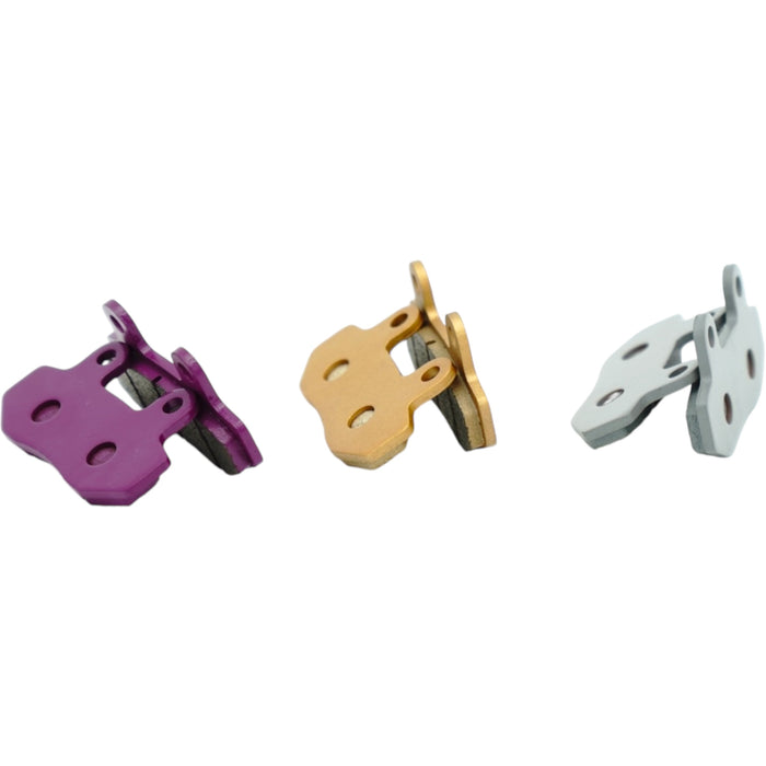 Sets of purple, gold, and silver bicycle disc brake pads on white background.