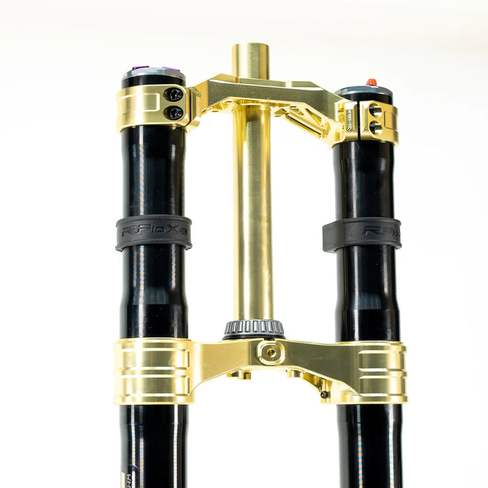 Gold and black motorcycle suspension fork triple clamp with steering tube.