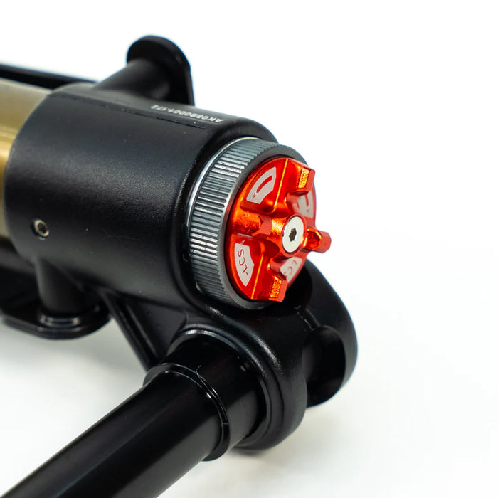 Close-up of a black and red adjustable shock absorber component on white background.