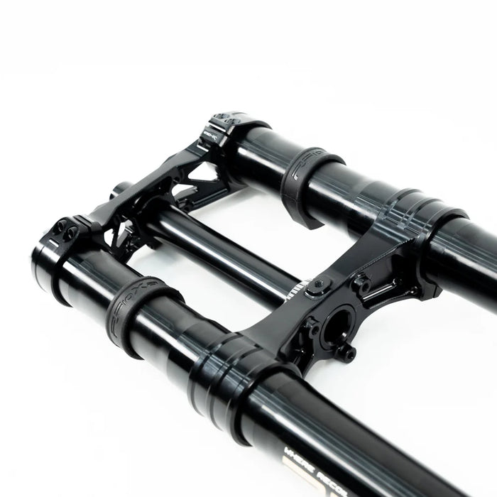 Black mountain bike suspension fork lowers with triple clamp on white background.